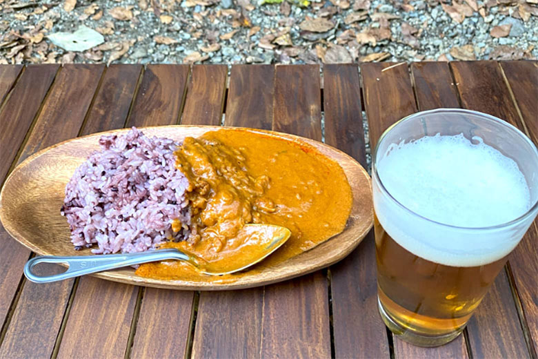 「骨付き肉が丸ごと入ったバターチキンカレーをかけた黒米」写真